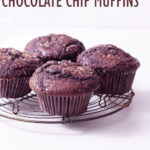 Straight on shot of Double Chocolate Chip Muffins on a wire rack on a white surface.