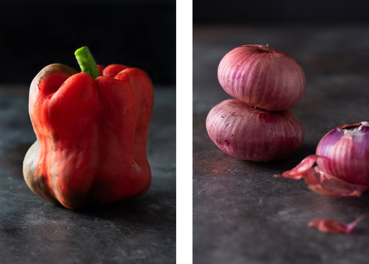 Side by side shots of a close up straight on shot of a red bell pepper on a dark grey textured surface with a black background; and a straight on shot of 2 mini red onions stacked on top of each other near a partially peeled onion on a dark grey textured surface.