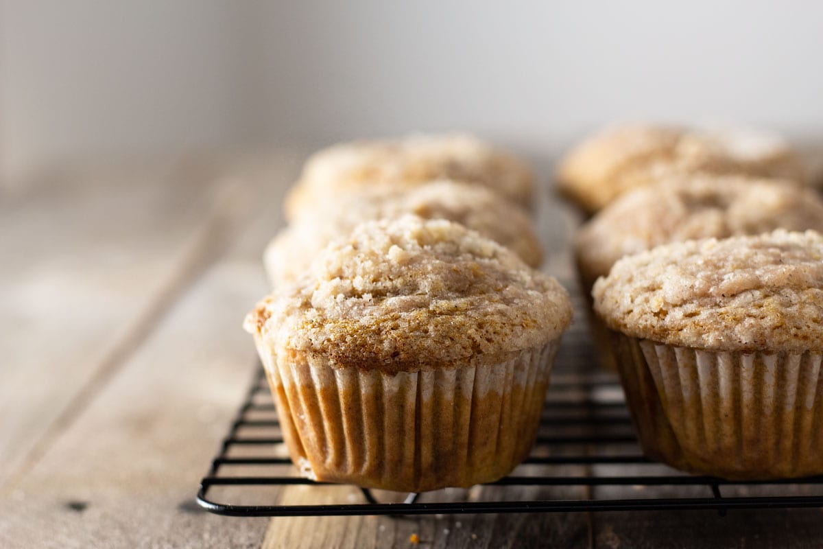 Straight on shot of a rack of Pumpkin Cream Cheese Streusel Muffins on a grey wood surface with a light background.