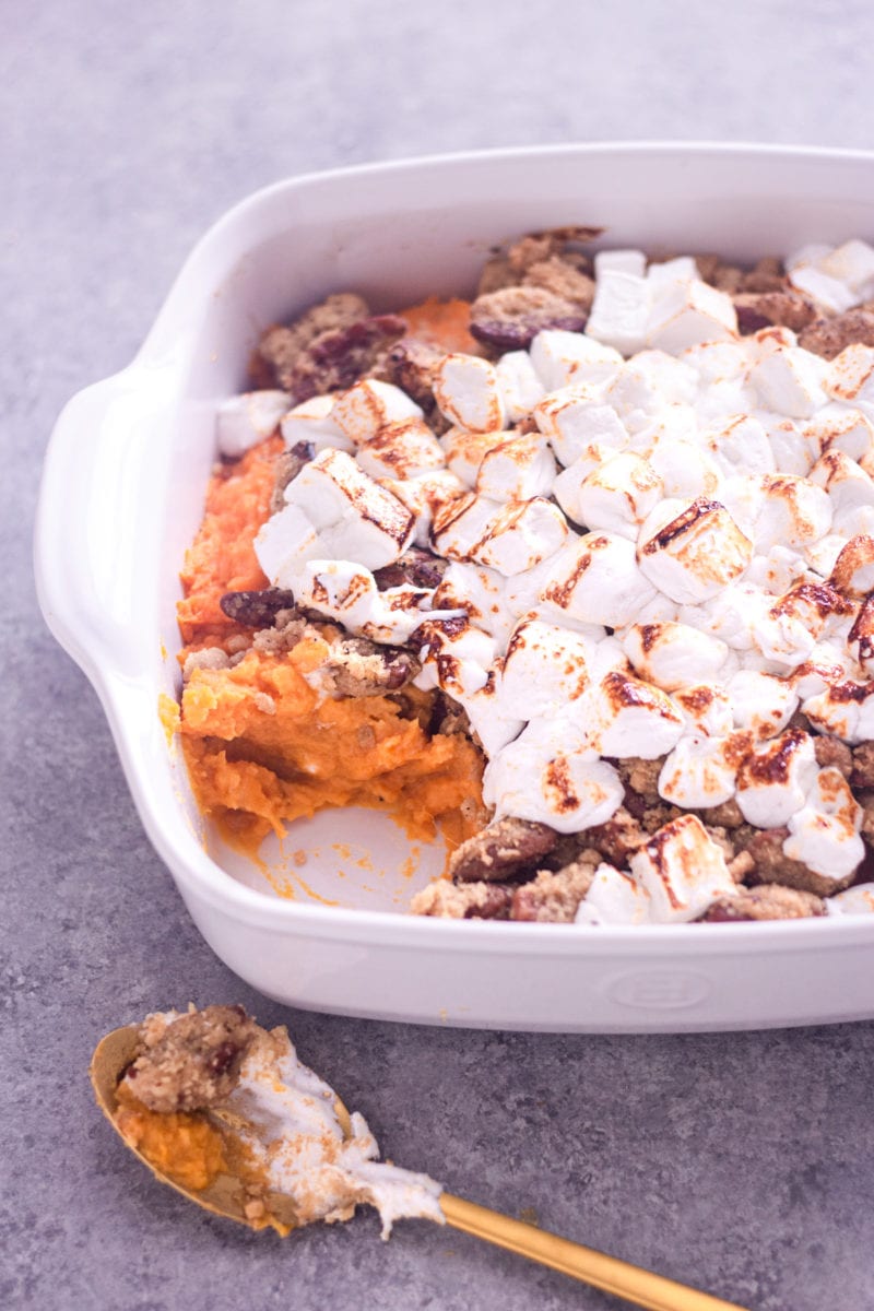 Angled view of sweet potato casserole with marshmallows and brown butter pecan topping in a casserole dish.