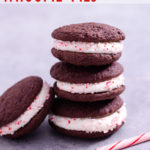 Straight on view of a stack of 3 Chocolate Peppermint Whoopie Pies with another whoopie pie leaning against the rest, next to a candy can with a light grey background.