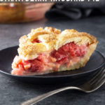 Straight on view of a slice of strawberry rhubarb pie on a dark plate on a dark grey surface.