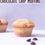 Close up, straight on view of a muffin with chocolate chips on a white surface with a light blue background.
