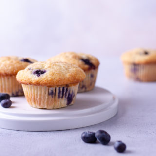 Straight on shot of a plate of Lemon Blueberry Muffins with a light blue background.