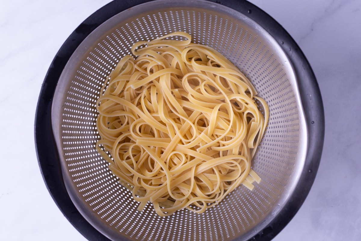 Overhead view of cooked fettuccine pasta drained in a colander.