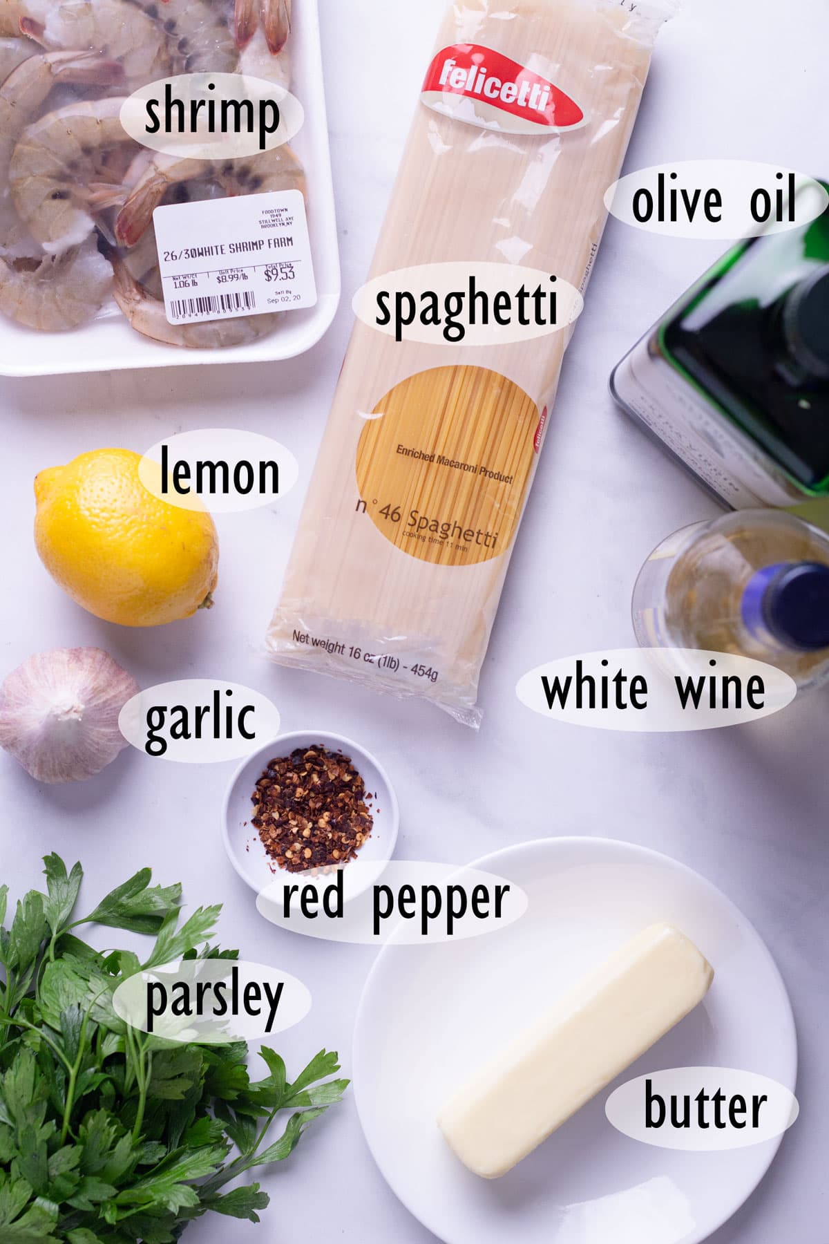 Individual ingredients needed for recipe, including shrimp, spaghetti, garlic, wine and butter.