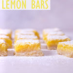 Straight on, close up view of cut lemon bars on parchment.