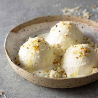 Three scoops of Milk and Honey Ice Cream with Milk Crumble in a rustic bowl on a light grey surface.