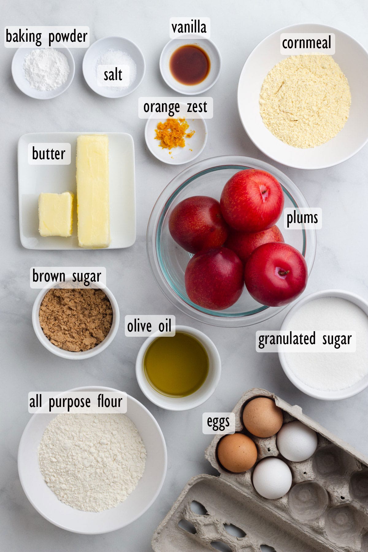 Cake Ingredients, including red plums, eggs, cornmeal, flour, white sugar, brown sugar, butter, olive oil, baking powder, salt, vanilla and orange zest.