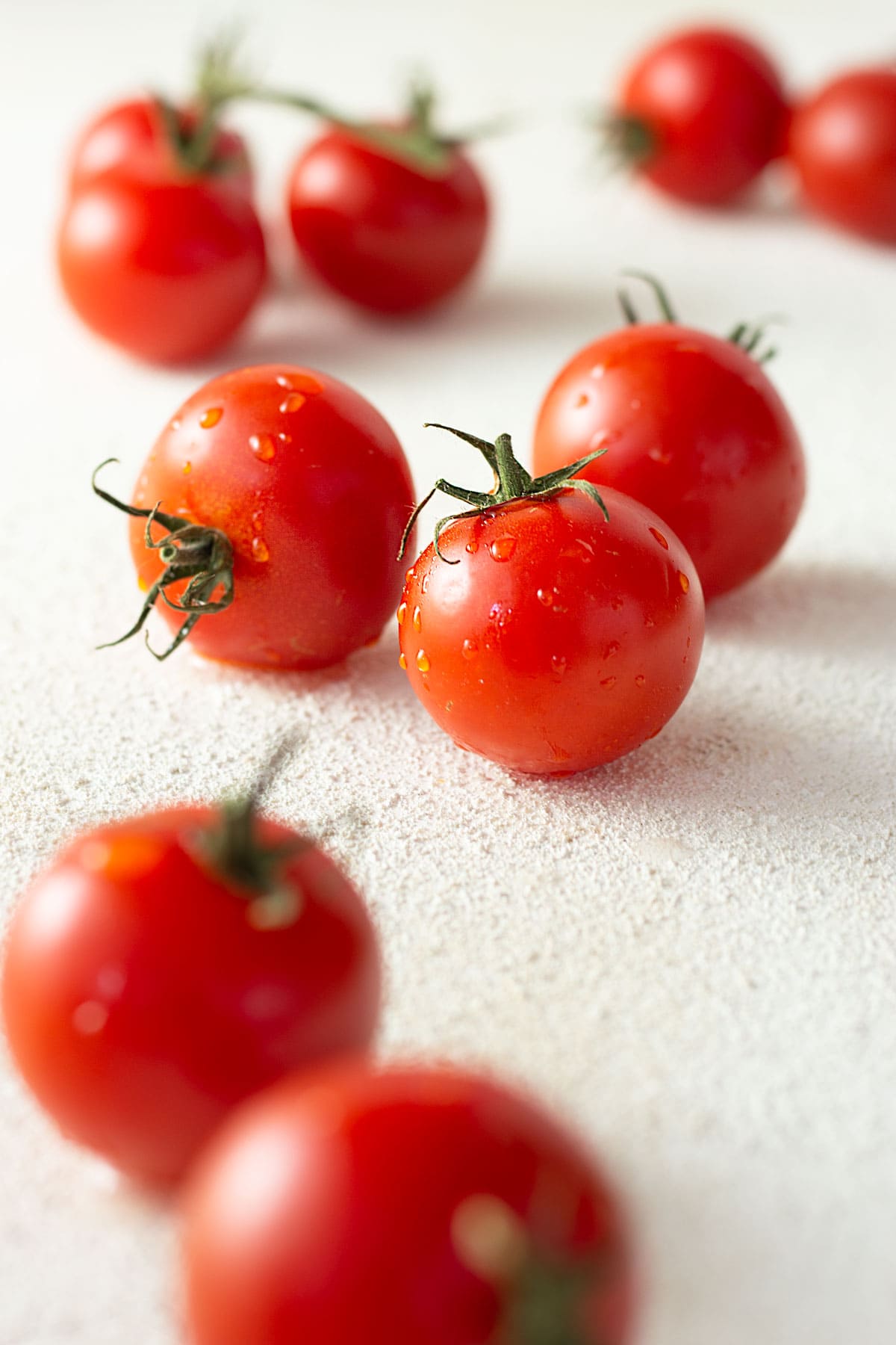Straight on close up view of a group of compari tomatoes with water droplets on them.