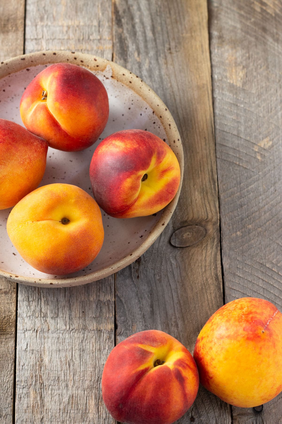 Group of fresh peaches on a rustic wood surface.