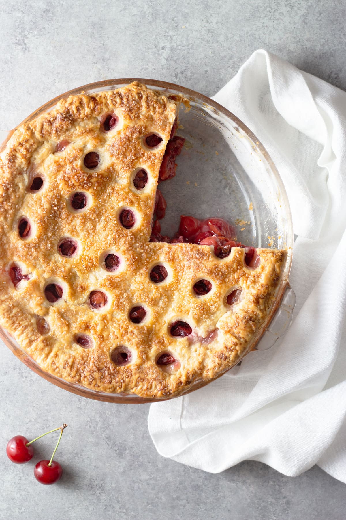 Overhead view of a sour cherry pie with a slice cut out and circles cut out of the top crust.