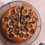 Sliced fig cake next to serving forks and plates.