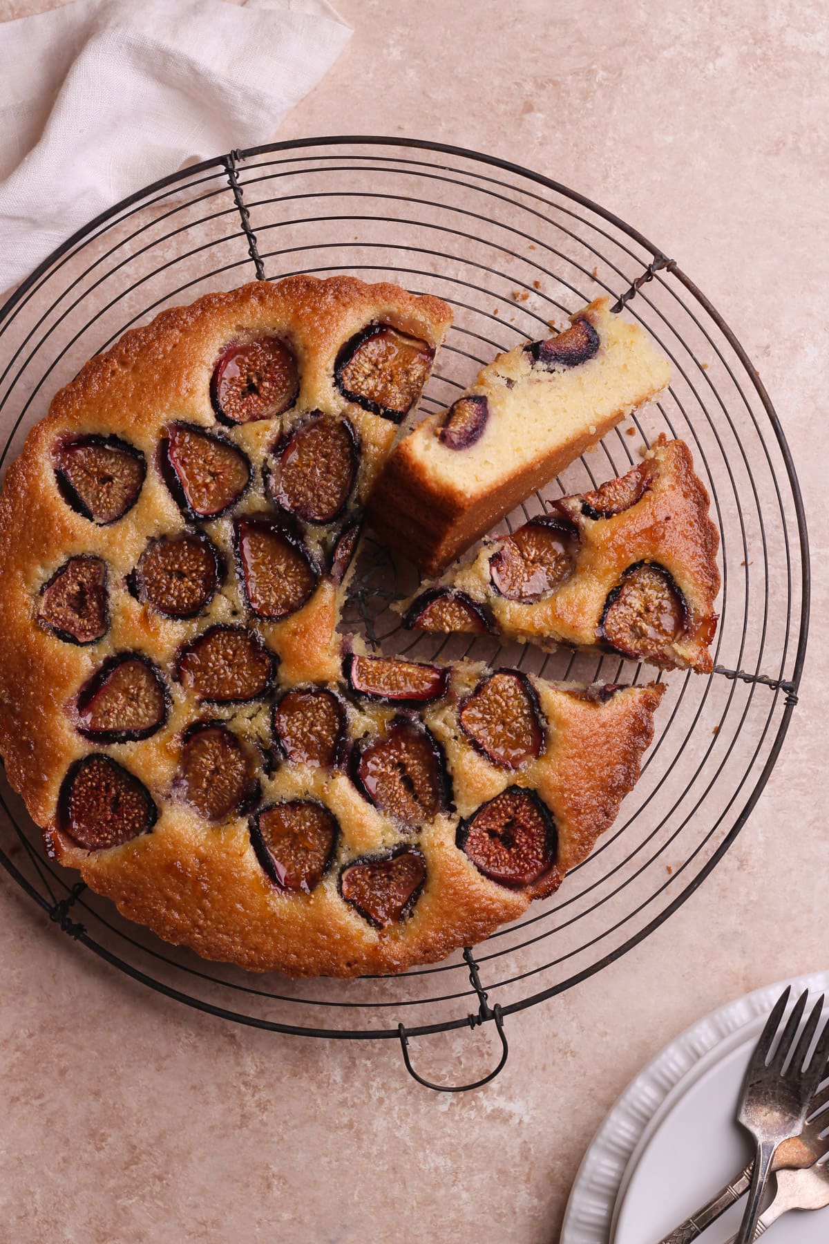 Fig cake with slices cut out on a wire rack.