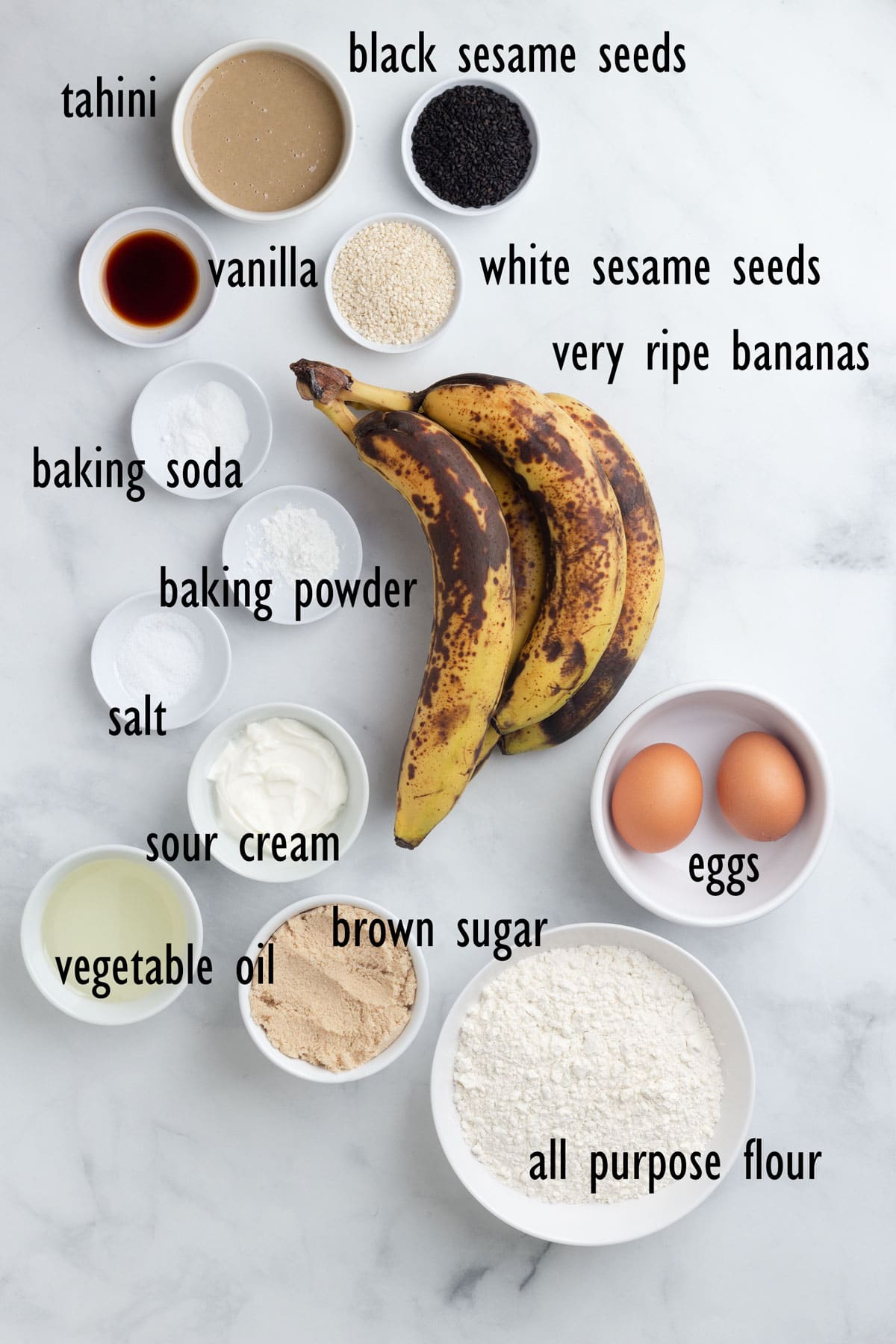 Banana Bread Ingredients including bananas, black and white sesame seeds, tahini, flour, brown sugar and eggs.