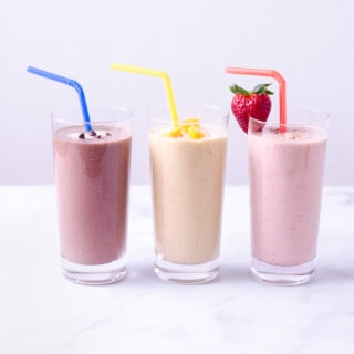 Three smoothies lined up: chocolate, mango and strawberry.