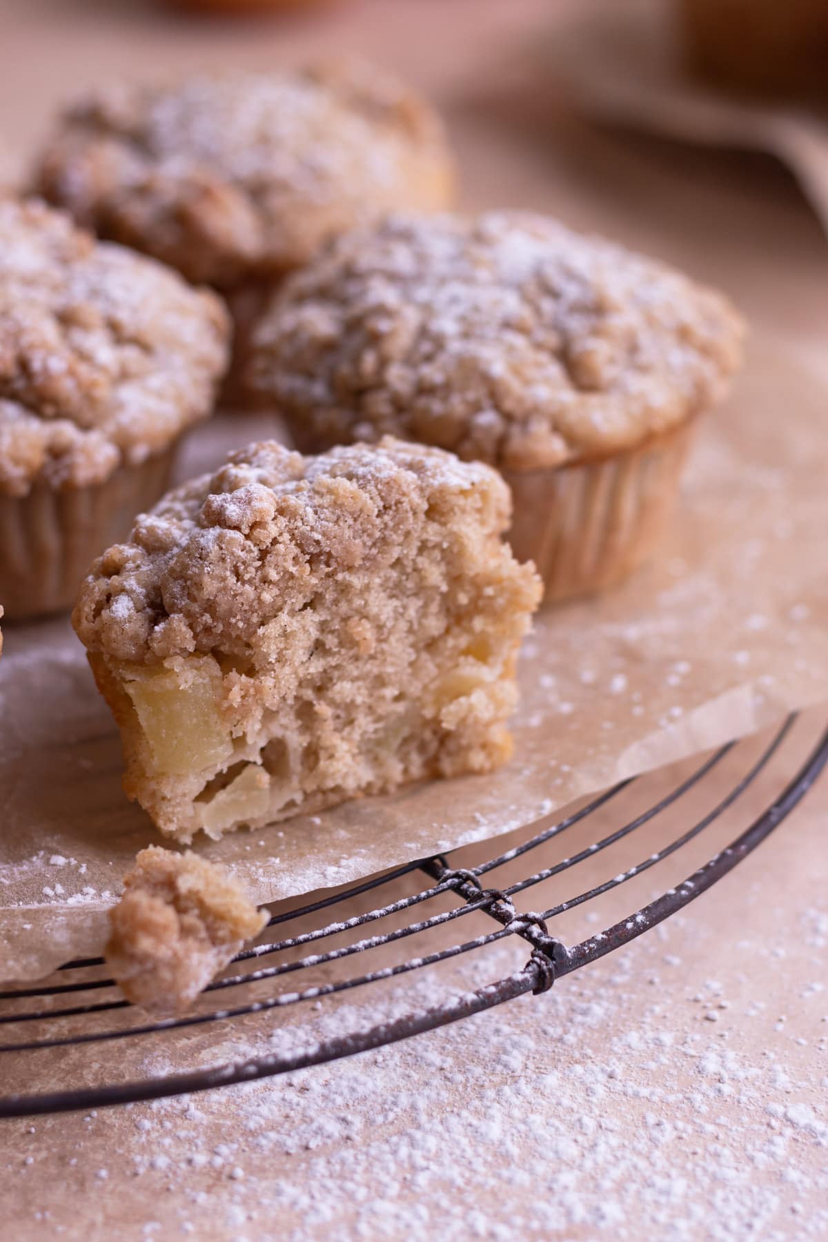 Close up of a cut open apple crumb muffins with more muffins in the background.