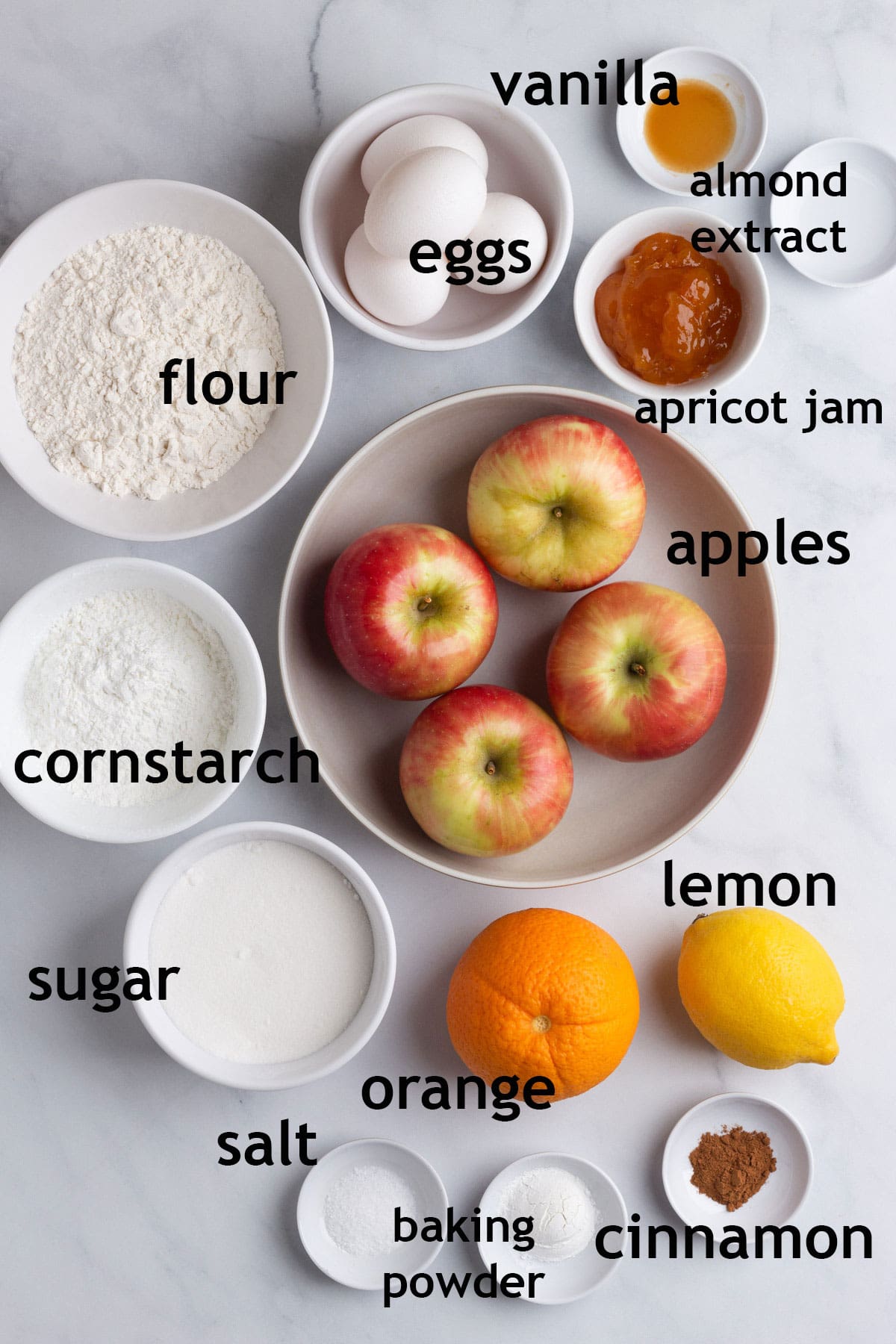 Cake ingredients, including apples, almond paste, flour, cornstarch, sugar, eggs, cinnamon and almond extract.