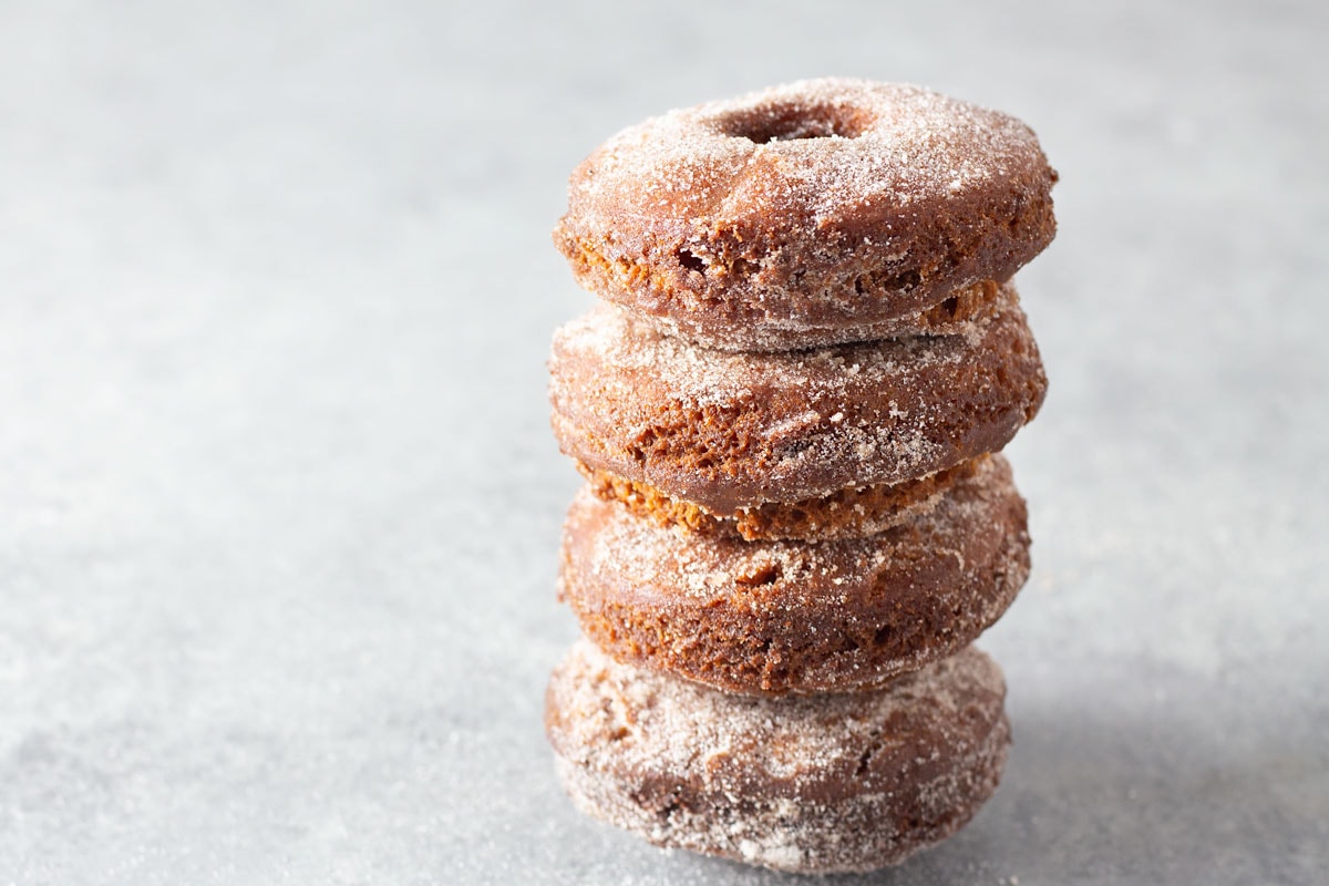 Apple Cider Donuts in a stack on a grey textured surface.