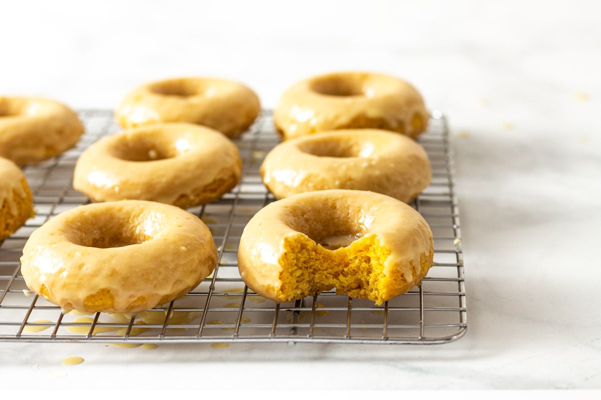 Straight on image of Baked Pumpkin Donuts with Maple Glaze on a wire rack.