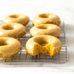 Straight on image of Baked Pumpkin Donuts with Maple Glaze on a wire rack.