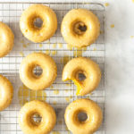 Overhead image of Baked Pumpkin Donuts with Maple Glaze on a wire rack on a marble surface.