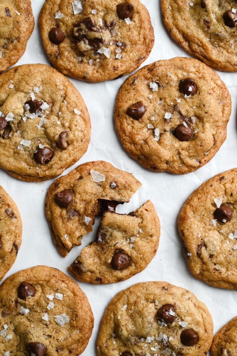 Overhead view of a cluster of salted chocolate chip cookies with one broken in half showing melted chocolate.
