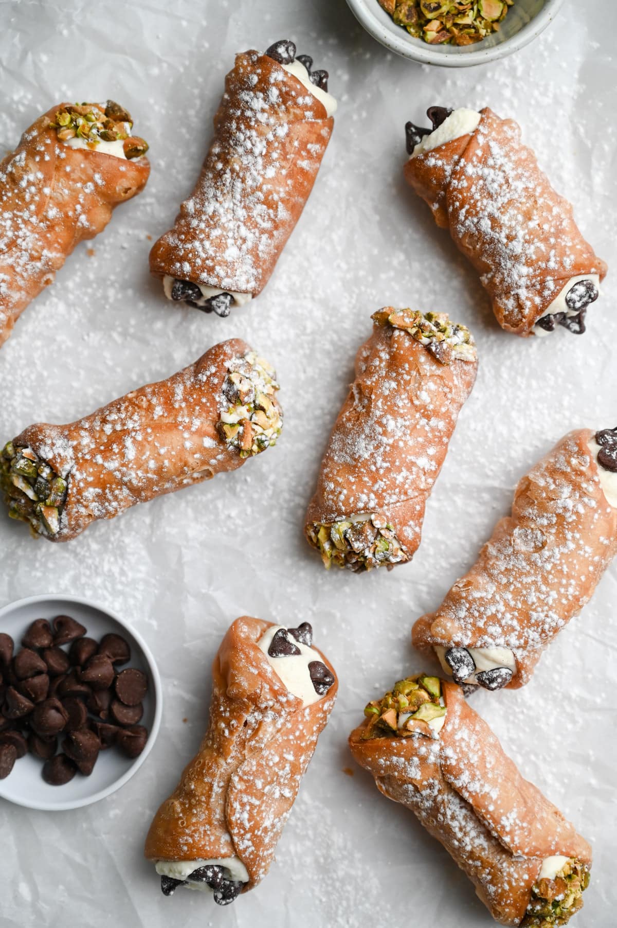 Overhead view of cannoli with ricotta mascarpone filling decorated with pistachios and chocolate chips.