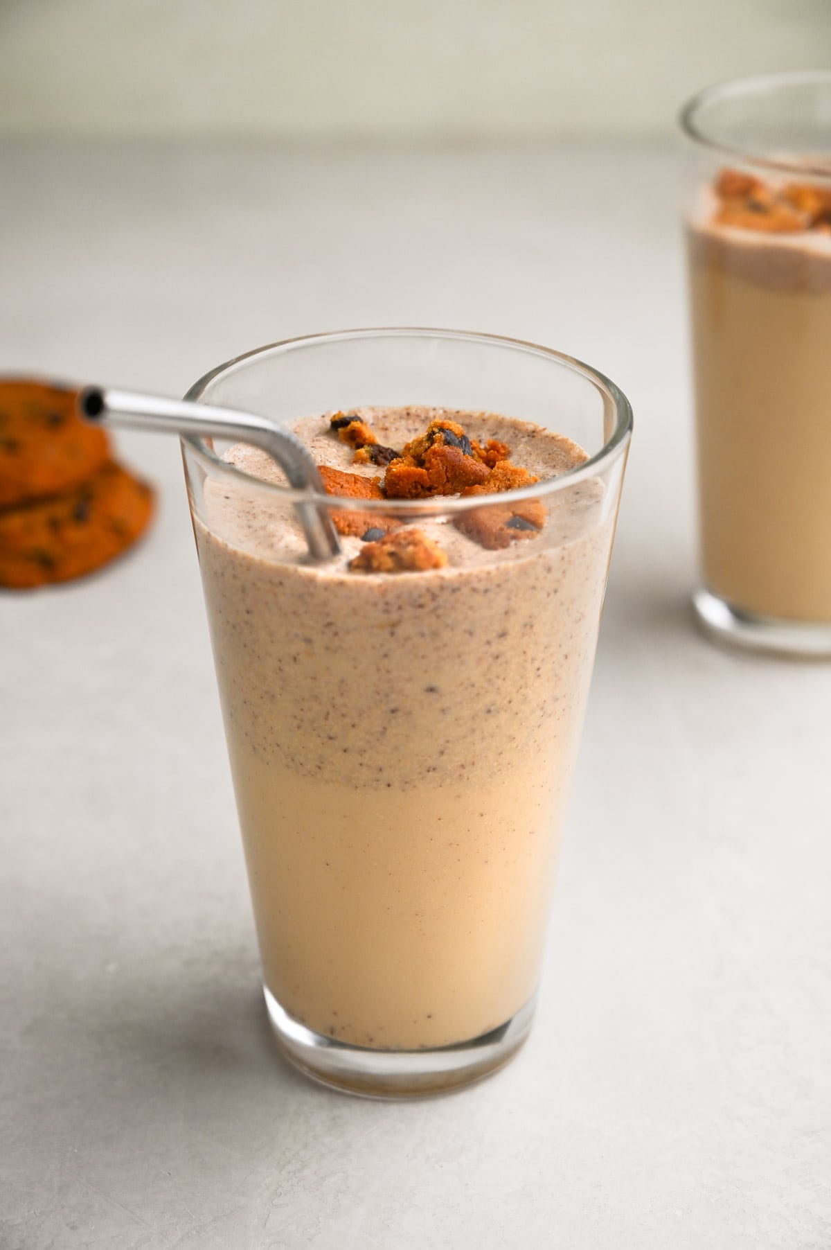 Close up angled view of a Cookies and Cream Protein Shake with cookies and another shake in the background.