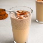 Close up angled view of a Cookies and Cream Protein Shake with cookies and another shake in the background.