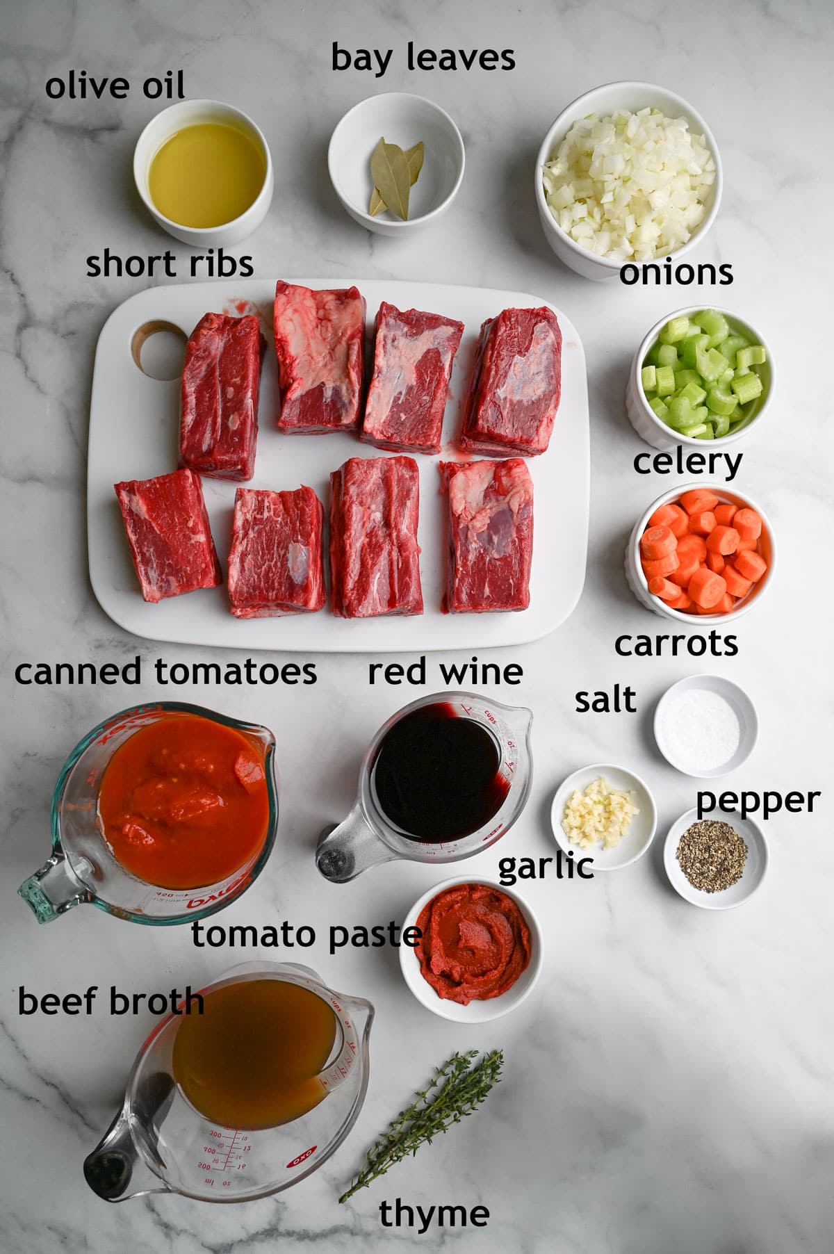 Ingredients including beef short ribs, onions, carrots, celery, canned tomatoes, tomato paste, garlic, broth and red wine.