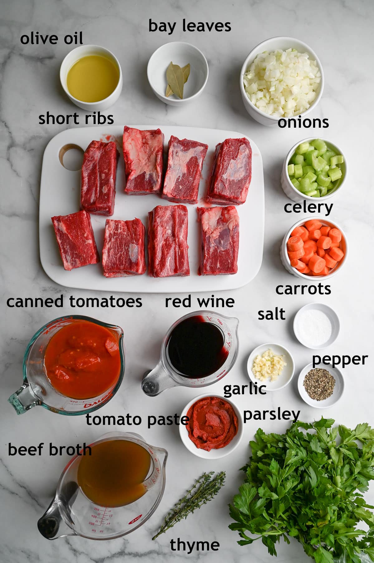 Ingredients including beef short ribs, onions, carrots, celery, canned tomatoes, tomato paste, garlic, broth and red wine.