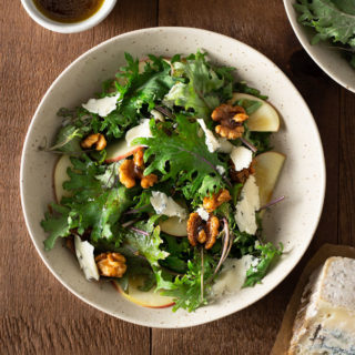 Overhead view of a bowl of Kale and Apple Salad with Walnuts and Blue Cheese.