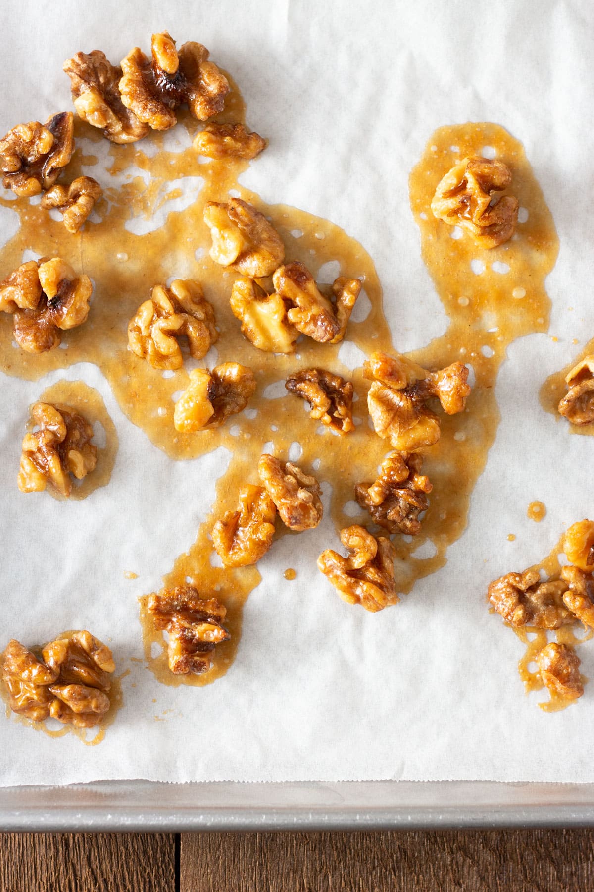Maple Butter Walnuts on white parchment on a sheet tray.