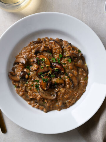 Closeup, overhead shot of a bowl of Mushroom Farro Risotto topped with parsley and lemon zest.