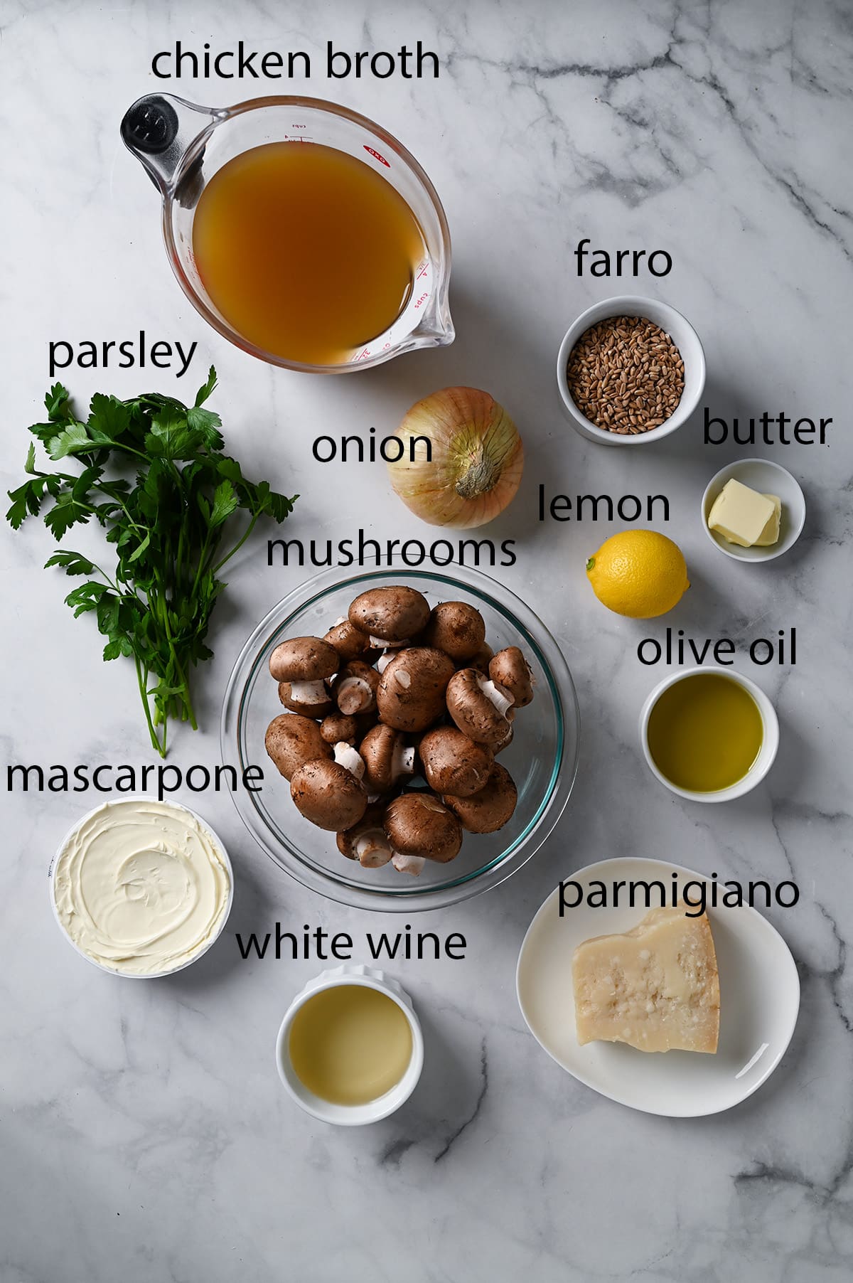 An overhead view of all the ingredients needed for mushroom farro risotto with labels. 